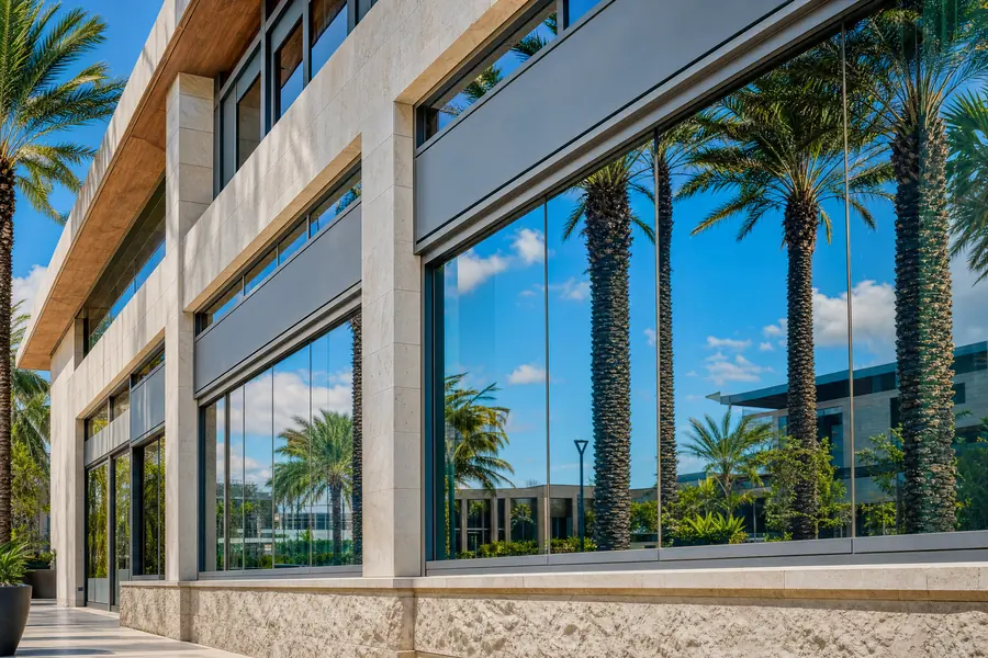 Commercial storefront glass reflecting palms and sky