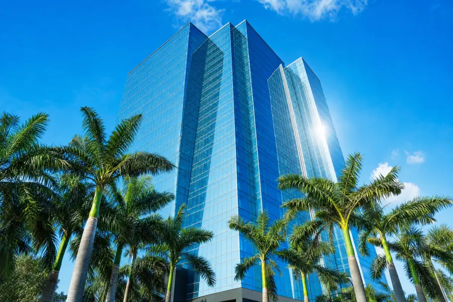 Modern glass office tower rising above palms in Miami